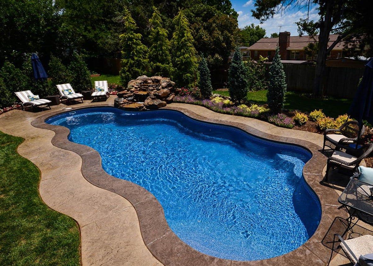 Liberty Devotion fiberglass pool, large freeform pool with curved concrete coping and deck, lounge chairs and landscaping, manufacturer photo.