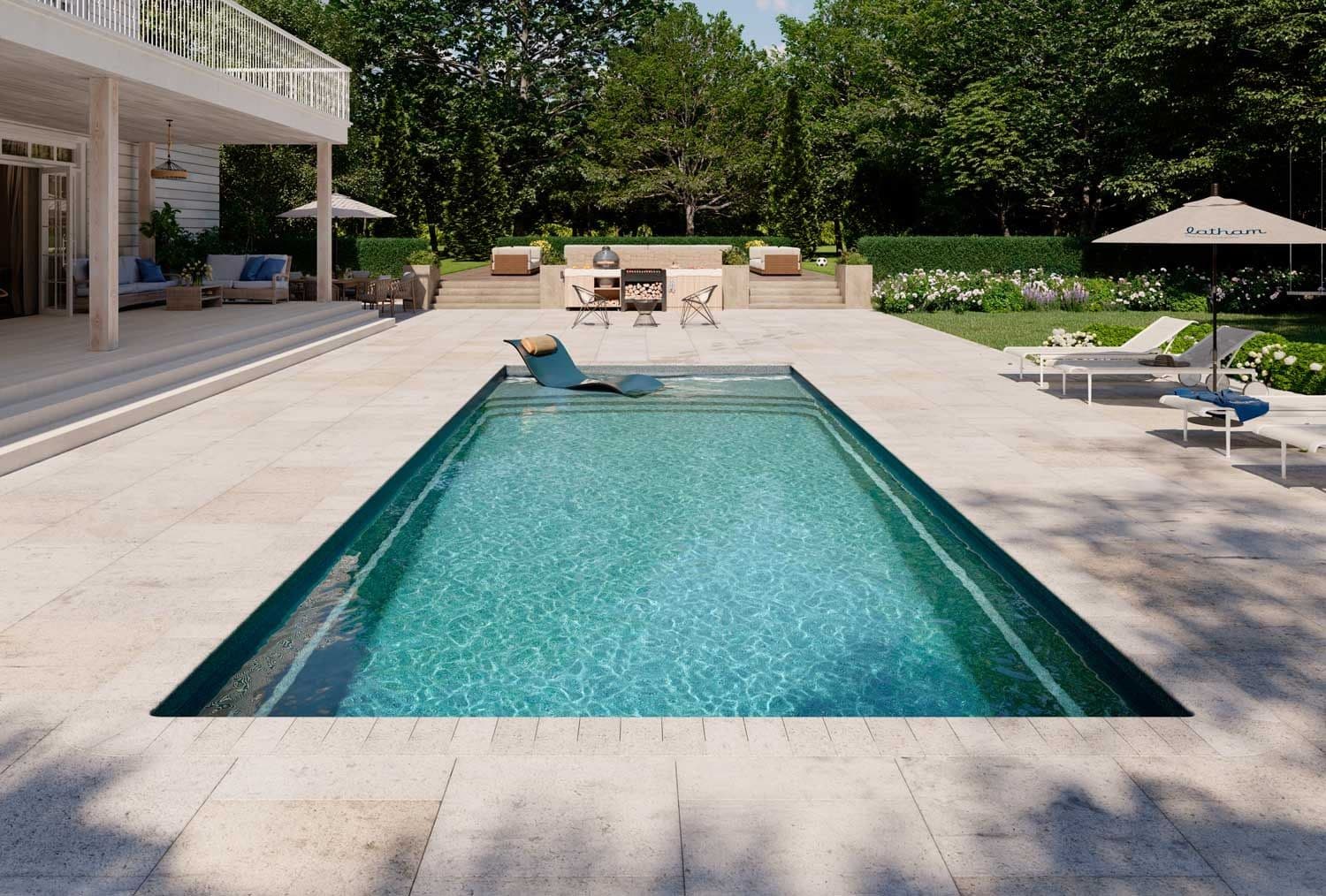 Liberty Heavenly fiberglass pool, rectangular pool with an in-water lounger, a light stone deck, lounge chairs and umbrellas, and a large house behind, manufacturer photo.