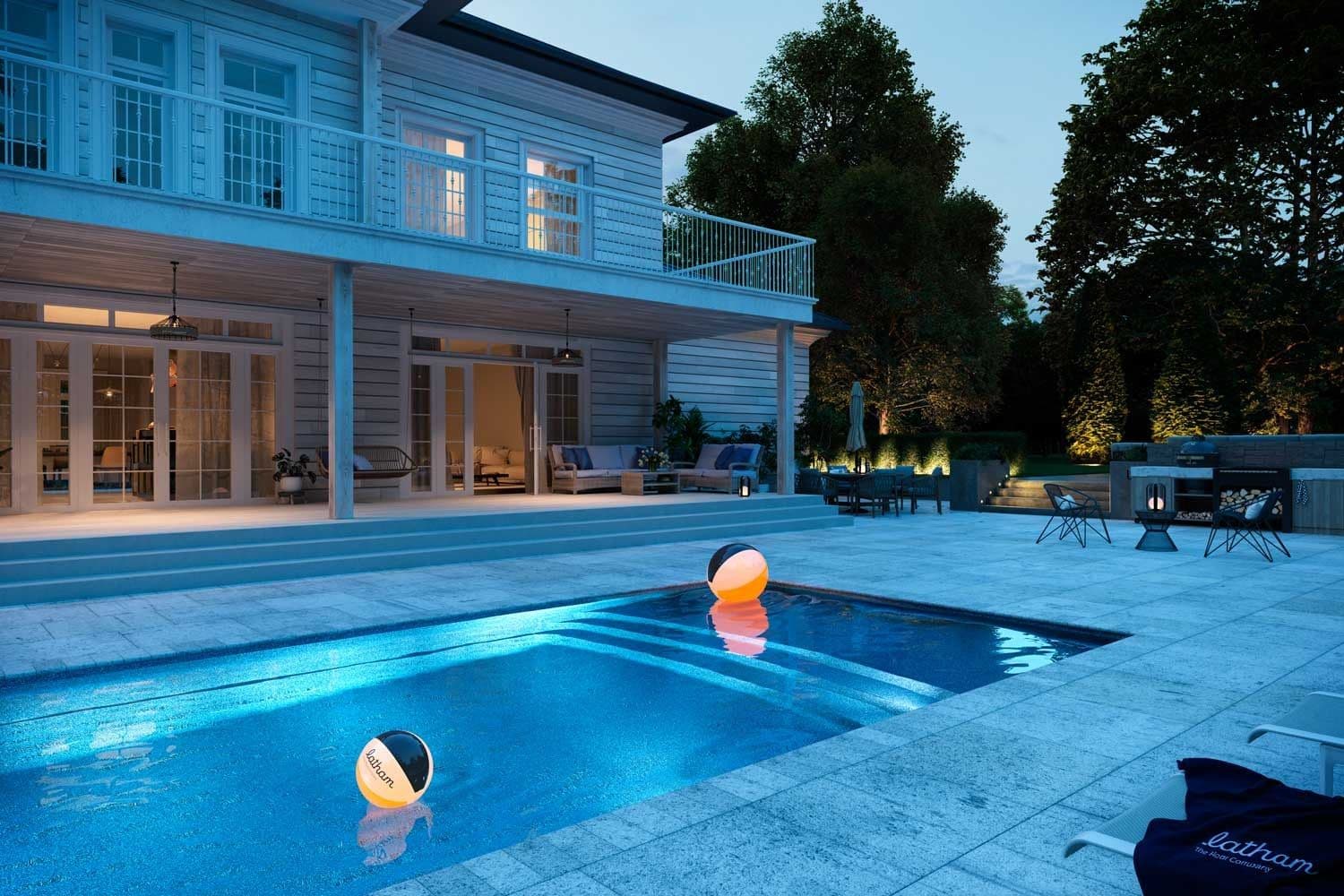 Liberty Heavenly fiberglass pool, rectangular pool lit at dusk with a floating light ball, stone deck and a white two-story house, manufacturer photo.