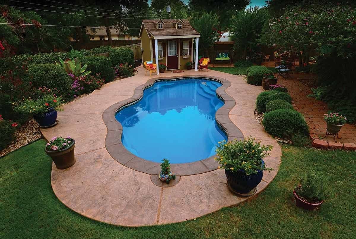 Liberty Relaxation fiberglass pool, freeform pool with a stamped concrete deck and potted plants in a garden with a small shed, seen from above, manufacturer photo.